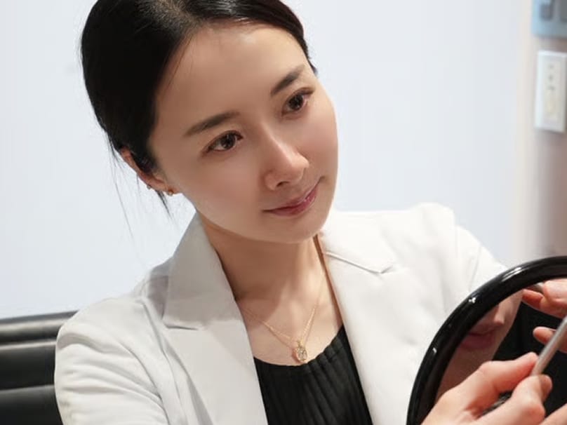 Doctor holding hand mirror during facial assessment