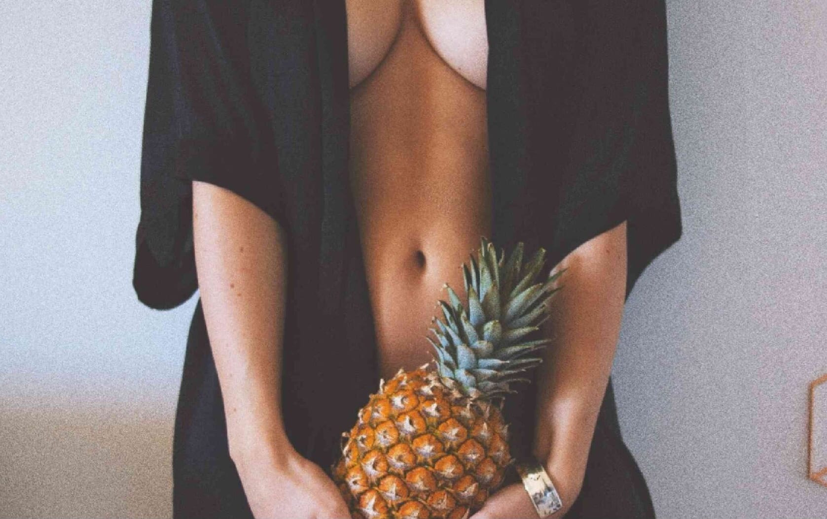 A woman holding fruit in front of her body