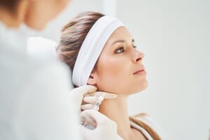 Cosmetic injection procedure on a woman's jawline.
