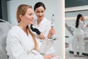 A woman viewing her results in a mirror after a cosmetic treatment.