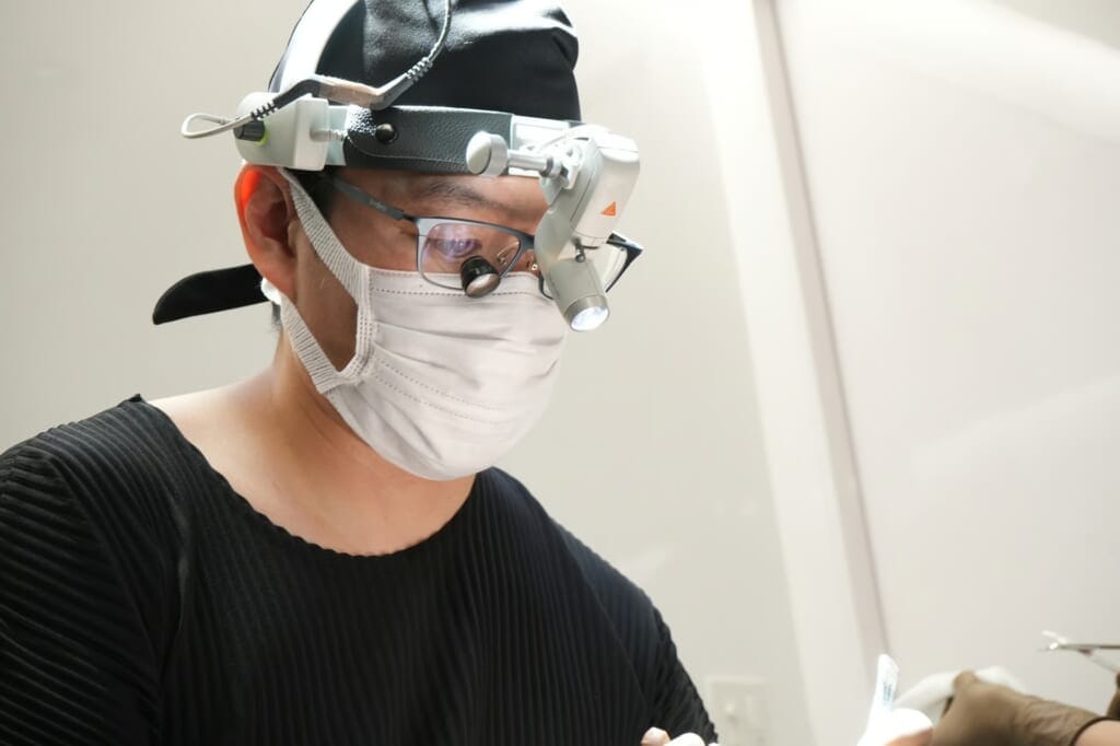Dr. Nakao during procedure, wearing surgical loupes and headlight
