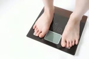 Overhead view of bare feet standing on a digital bathroom scale, representing weight management or diet tracking